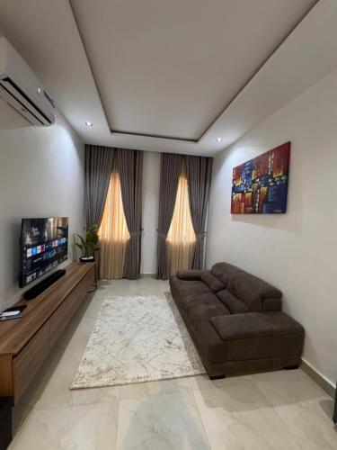 a living room with a couch and a flat screen tv at D-GioGiNiapartments in Gwarinpa