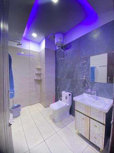a bathroom with a sink and a toilet and purple lighting at Revanta Home Stay in Anandpur Sāhib