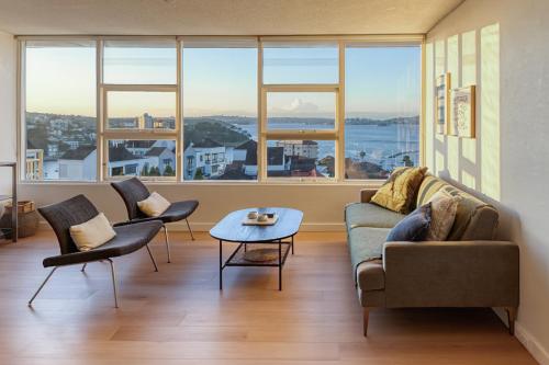 a living room with a couch and chairs and a table at Panoramic Harbour View Apartment in Sydney