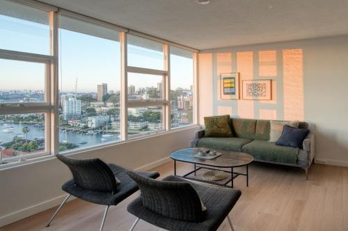 a living room with a couch and chairs and windows at Panoramic Harbour View Apartment in Sydney