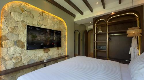 a bedroom with a tv on a stone wall at Hygge Hotel and Villas Seminyak in Seminyak