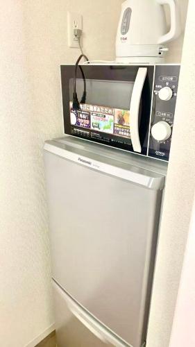 a white microwave sitting on top of a refrigerator at Lucky House 喜屋 in Osaka