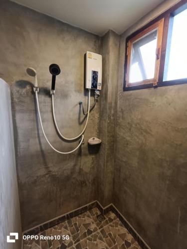a shower in a bathroom with a hose on the wall at Vela Resort Umphang in Ban Mae Klong Mai
