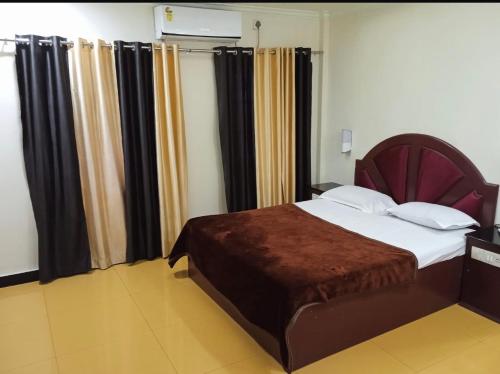 a bedroom with a bed with black and yellow curtains at Jaya Tourist Home in Varkala
