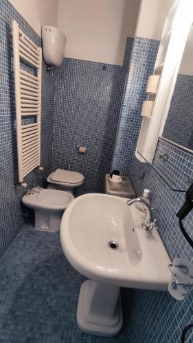 a blue tiled bathroom with a sink and a toilet at Casa Fornaciari in Viareggio