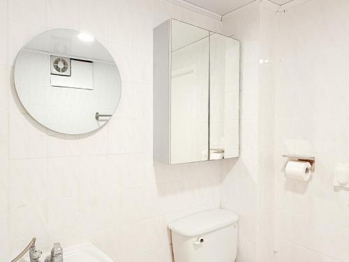 a white bathroom with a toilet and a mirror at Spacious 2BR Apartment near Subway Free Parking Seoul in Seoul