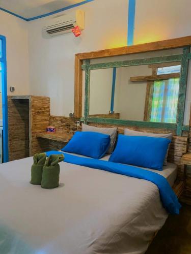 a bedroom with a large bed with blue pillows at Is Oke House in Gili Trawangan