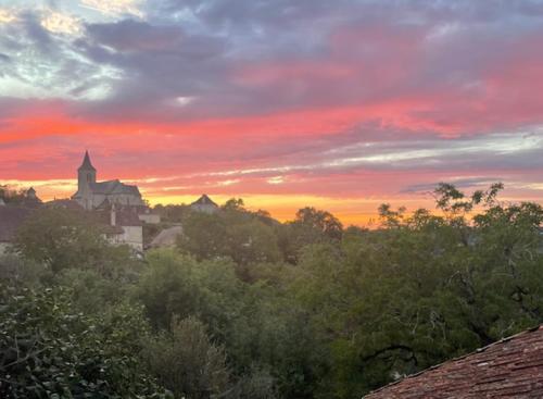 a sunset over a city with a church and trees at La Forge de Béduer in Béduer