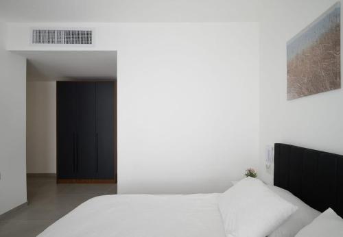 a bedroom with a white bed and a black door at 3BR charming on the 14th floor overlooking the sea in Qiryat Yam