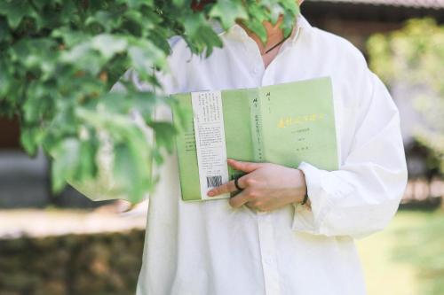 a man in a white shirt holding a book at Floral Moganshan Natural Residence Pet Resort B&B in Huzhou