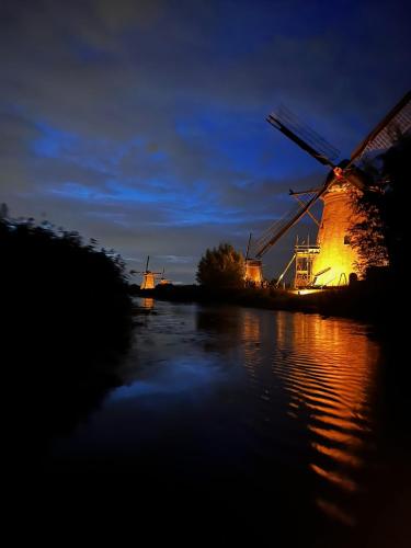 a night view of a windmill on a river at B&B appartement Rebel and Moon in het centrum van Alblasserdam in Alblasserdam