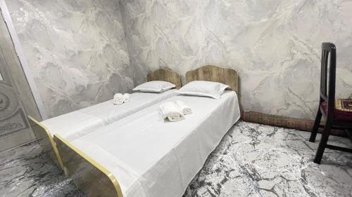 a white bed with towels on it in a room at Adashboy Palace Family Guest House in Samarkand