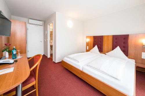 Habitación de hotel con cama grande y escritorio. en Hotel Vater Rhein en Wörth am Rhein