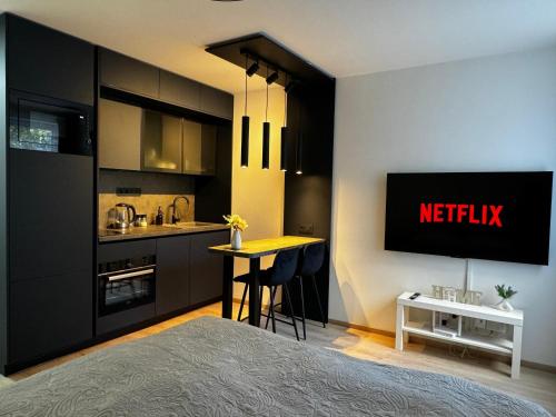 a bedroom with a bed and a kitchen with a tv at Smarty Choice Living with Netflix - Kubánské náměstí in Prague