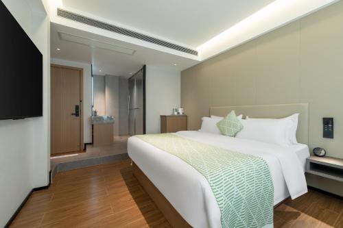 a bedroom with a large white bed and a bathroom at Xiaduo B&B in Wangjiazhai