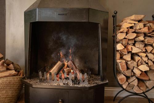 a fire in a fireplace next to a pile of logs at Aan d'Oewer in Citrusdal
