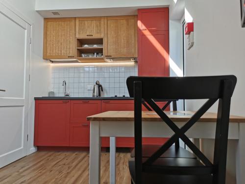 a kitchen with red cabinets and a black chair at Ant marių kranto-By the Lagoon Apartments in Preila