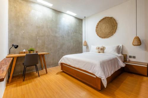 a bedroom with a bed and a desk with a chair at SNUG Kuta in Kuta