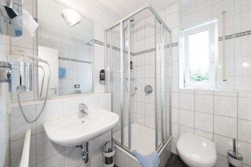 een witte badkamer met een wastafel en een douche bij Hotel Vater Rhein in Wörth am Rhein