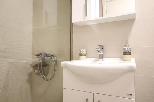 a bathroom with a white sink and a shower at Bright Modern Holiday Home With Postcard Lake View in Pluzine