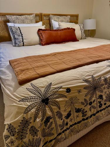 a bed with a comforter with palm trees on it at Budgaribah in Old Bar