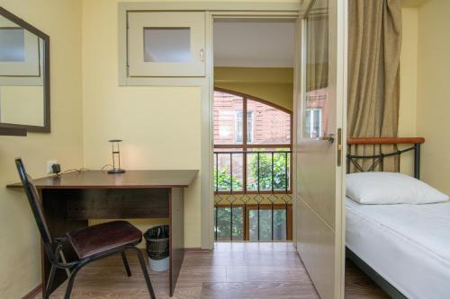 Un dormitorio con un escritorio y una cama y una ventana. en Apartment Nebula Rooms, en Tiflis