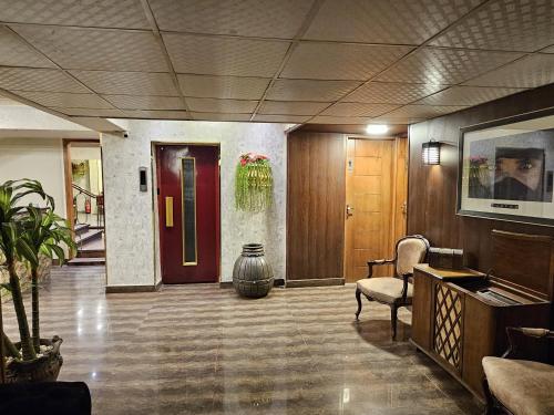 a lobby with a red door and a chair and a piano at Oasis Heliopolis Hotel-فندق أوازيس هليوبوليس in Cairo