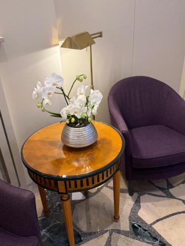 a table with a vase of flowers on it next to two chairs at Hotel Liebig in Frankfurt/Main