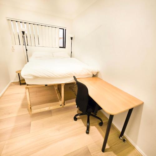 Un dormitorio con una cama y un escritorio con una silla de escritorio. en The Frederick Guest House, en Sídney
