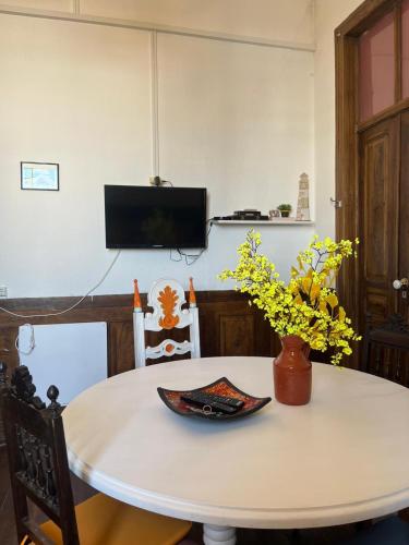 a white table with a vase of flowers on it at Solar Das Marés in Fuzeta