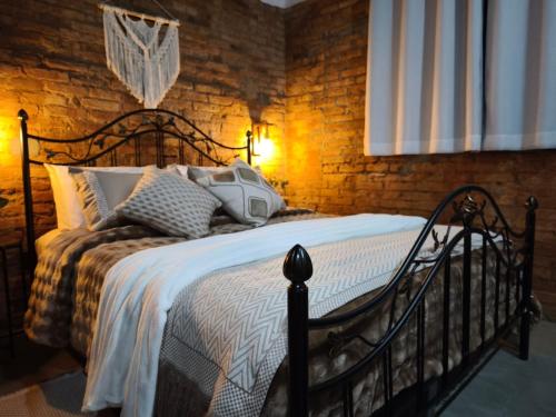a bed in a room with a brick wall at Vale Infinito Chalé in Córrego do Bom Jesus