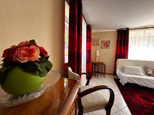 a vase with a rose on a table in a living room at La Petite Source in Dabo
