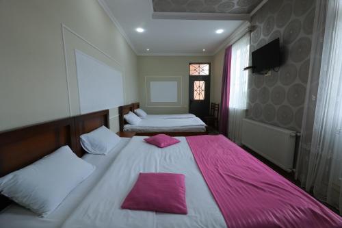 a bedroom with two beds with pink pillows on them at Hotel Harmony in Kutaisi