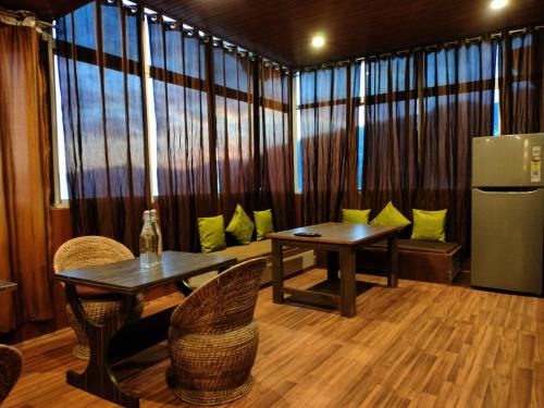 a room with a table and chairs and a refrigerator at The Valley Vista Resort Gangtok with Mountain View in Gangtok