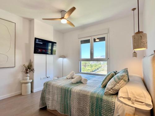 a bedroom with a bed with a ceiling fan and a window at Playa Granada Apartamentos Moriscos II in Motril