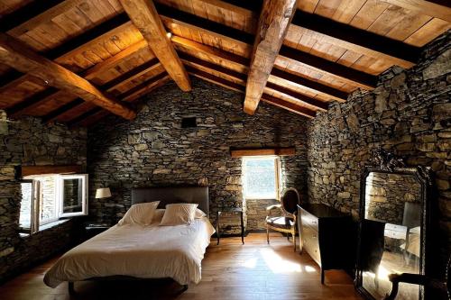 a bedroom with a large bed in a stone wall at Bergerie in Volpajola