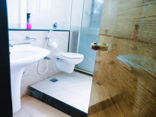 a bathroom with a shower and a toilet and a sink at Athasri Hotel Infantry Road in Bengaluru