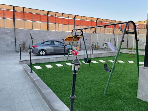 a playground with swings and a car in a parking lot at Oriana - your sanctuary escape in Amman