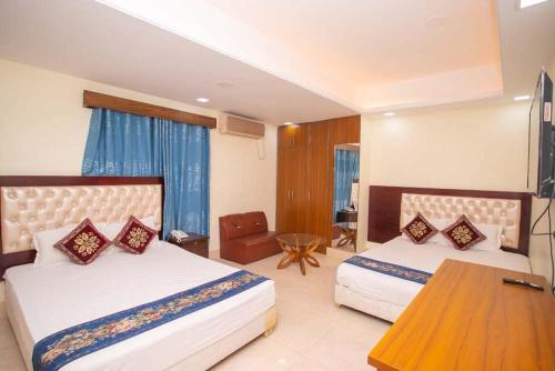 a hotel room with two beds and a table at Hotel D Palace in Dhaka