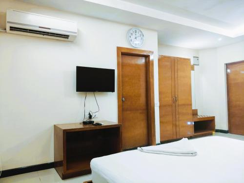 a bedroom with a bed and a tv on a wall at Athasri Hotel Infantry Road in Bengaluru