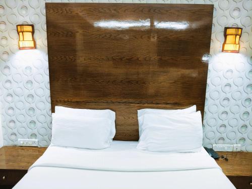 a bed with two pillows and a wooden headboard at Athasri Hotel Infantry Road in Bengaluru