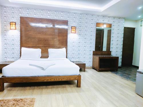 a bedroom with a bed with a wooden headboard at Athasri Hotel Infantry Road in Bengaluru
