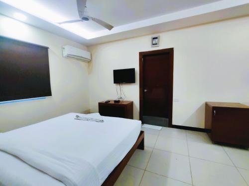 a bedroom with a bed and a flat screen tv at Athasri Hotel Infantry Road in Bengaluru