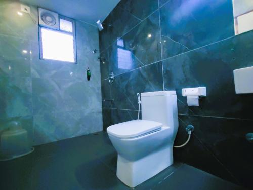 a bathroom with a toilet and a blue tiled wall at Athasri Hotel Infantry Road in Bengaluru