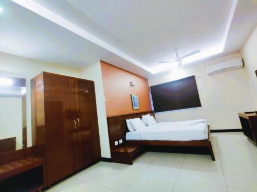a hotel room with a bed and a tv at Athasri Hotel Infantry Road in Bengaluru