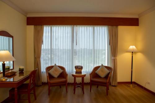 a living room with a table and chairs and a large window at CS Pattani Hotel in Ban Ru Sa Mi Lae