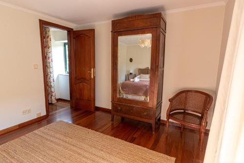 a room with a dresser with a mirror and a chair at Casa das Regueiras in Santiago de Compostela