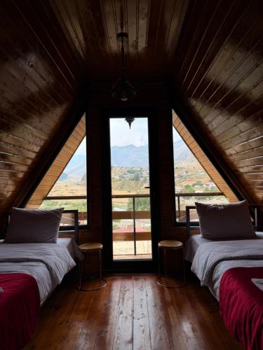 two beds in a room with a large window at Donata Cottages kazbegi in Stepantsminda