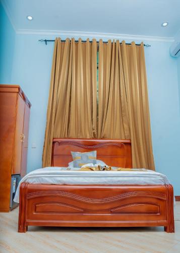 a bed with a wooden frame in a bedroom at Advem Villa in Dodoma