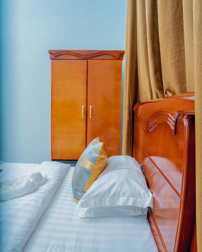 a bed with two pillows and a wooden headboard at Advem Villa in Dodoma